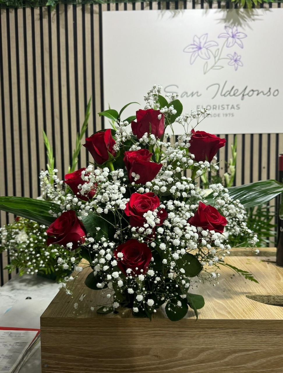 Centro delante del mostrador de la floristería San Ildefonso con rosas rojas