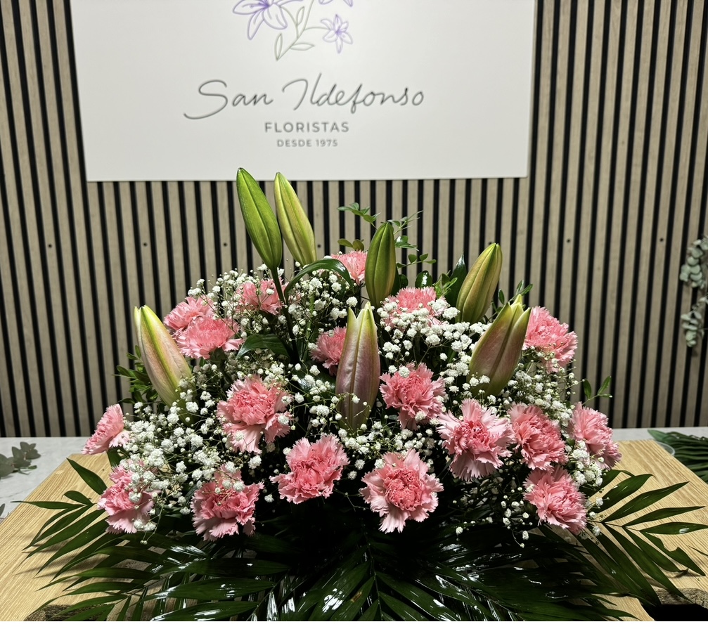 Centro delante del mostrador de la floristería San Ildefonso con claveles rosas y lírios