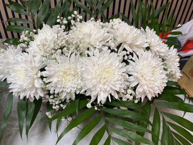 Centro delante del mostrador de la floristería San Ildefonso con con crisantemos blancos