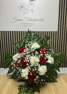 Arreglo delante del mostrador de la floristería San Ildefonso con claveles rojos y blancos