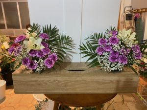 Jardinera delante del mostrador de la floristería San Ildefonso con rosas lilas