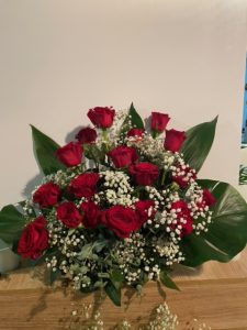 Jardinera delante del mostrador de la floristería San Ildefonso con rosas rojas