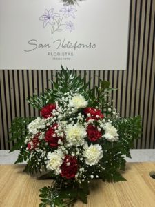 Arreglo delante del mostrador de la floristería San Ildefonso con claveles rojos y blancos