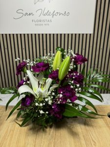 Arreglo delante del mostrador de la floristería San Ildefonso en tonos morados con lírios