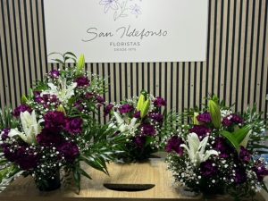 Varios arreglos delante del mostrador de la floristería San Ildefonso en tonos morados