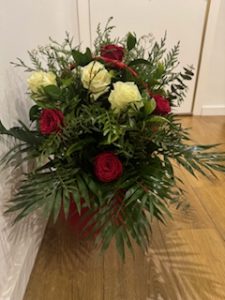 Ramo delante del mostrador de la floristería San Ildefonso en tonos rojos