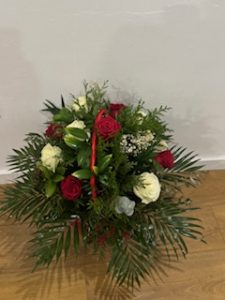 Ramo delante del mostrador de la floristería San Ildefonso en tonos rojos