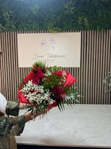 Ramo delante del mostrador de la floristería San Ildefonso en tonos rojos